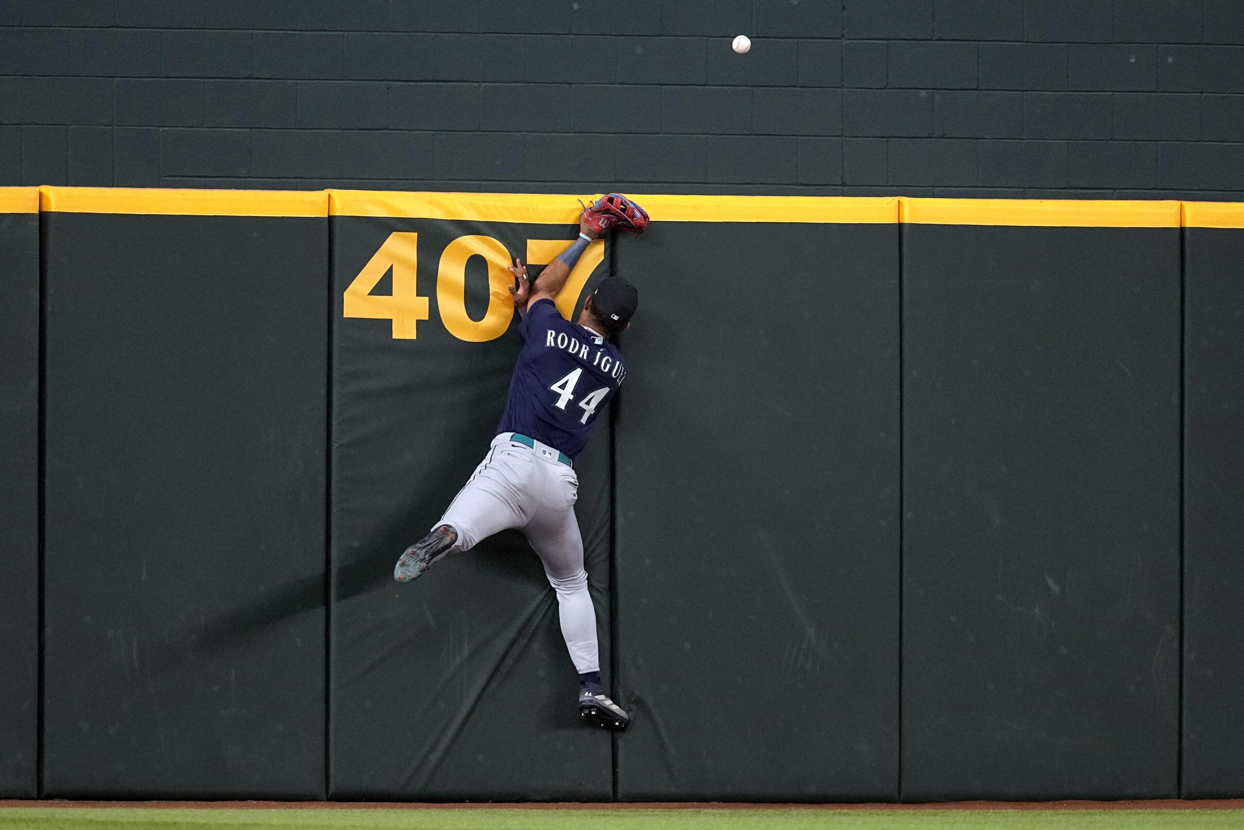 Seattle Mariners' Julio Rodriguez slams against the wall after attempting to make a play on a home run ball hit by Texas Rangers' Leody Taveras in the fourth inning of a baseball game, Sunday, Sept. 24, 2023, in Arlington, Texas.