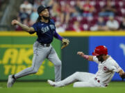Seattle Mariners' J.P. Crawford, left, forces out Cincinnati Reds' Nick Martini at second base as he throws to first base to complete the double play during the eighth inning of a baseball game in Cincinnati, Wednesday, Sept. 6, 2023.