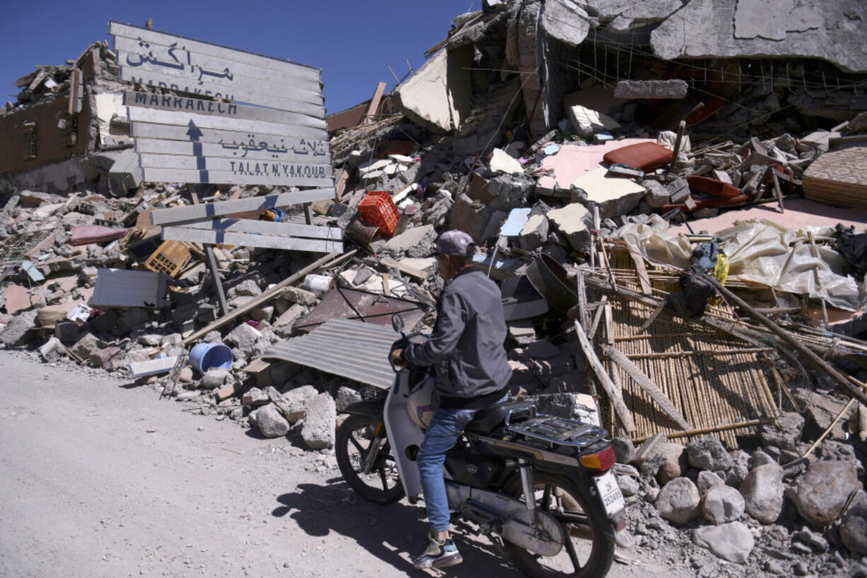 A man on a scooter drives past rubble and a damaged road sign pointing to Marrakech in Talat N'yakoub, Morocco, Monday Sept. 11, 2023. More than 2,000 people were killed, and the toll was expected to rise as rescuers struggled to reach hard-hit remote areas after a powerful earthquake struck Morocco.