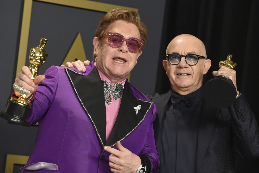 FILE - Elton John, left, and Bernie Taupin, winners of the award for best original song for "(I'm Gonna) Love Me Again" from "Rocketman", pose in the press room at the Oscars on Sunday, Feb. 9, 2020, in Los Angeles. Taupin's memoir, "Scattershot: Life, Music, Elton, and Me" releases this week.
