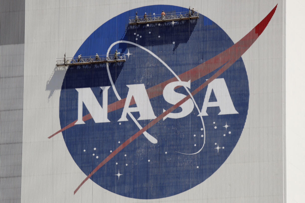 FILE - Workers on scaffolding repaint the NASA logo near the top of the Vehicle Assembly Building at the Kennedy Space Center in Cape Canaveral, Fla., Wednesday, May 20, 2020. After a yearlong study into UFOs, NASA is releasing a report Thursday, Sept. 14, 2023, on what it needs to better understand unidentified flying objects from a scientific point of view.