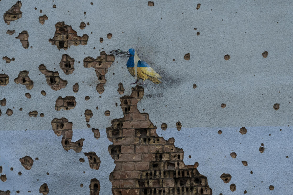 FILE - A dove painted by artist TvBoy adorns the wall of a building damaged by Russian shelling attacks in Irpin, Ukraine, Friday, July 7, 2023. Life in the capital of a war-torn country seems normal on the surface. In the mornings, people rush to their work holding cups of coffee. Streets are filled with cars, and in the evenings restaurants are packed. But the details tell another story. (AP Photo/Jae C.