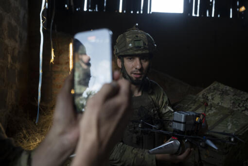 A Ukrainian soldier, nicknamed Stem, presents an attack drone he just loaded with shells for a social media post in the outskirts of Kremmina, Ukraine, Sunday, Aug. 20, 2023. The drone unit's task is to destroy Russia's heavy machinery, armored vehicles and infantry.