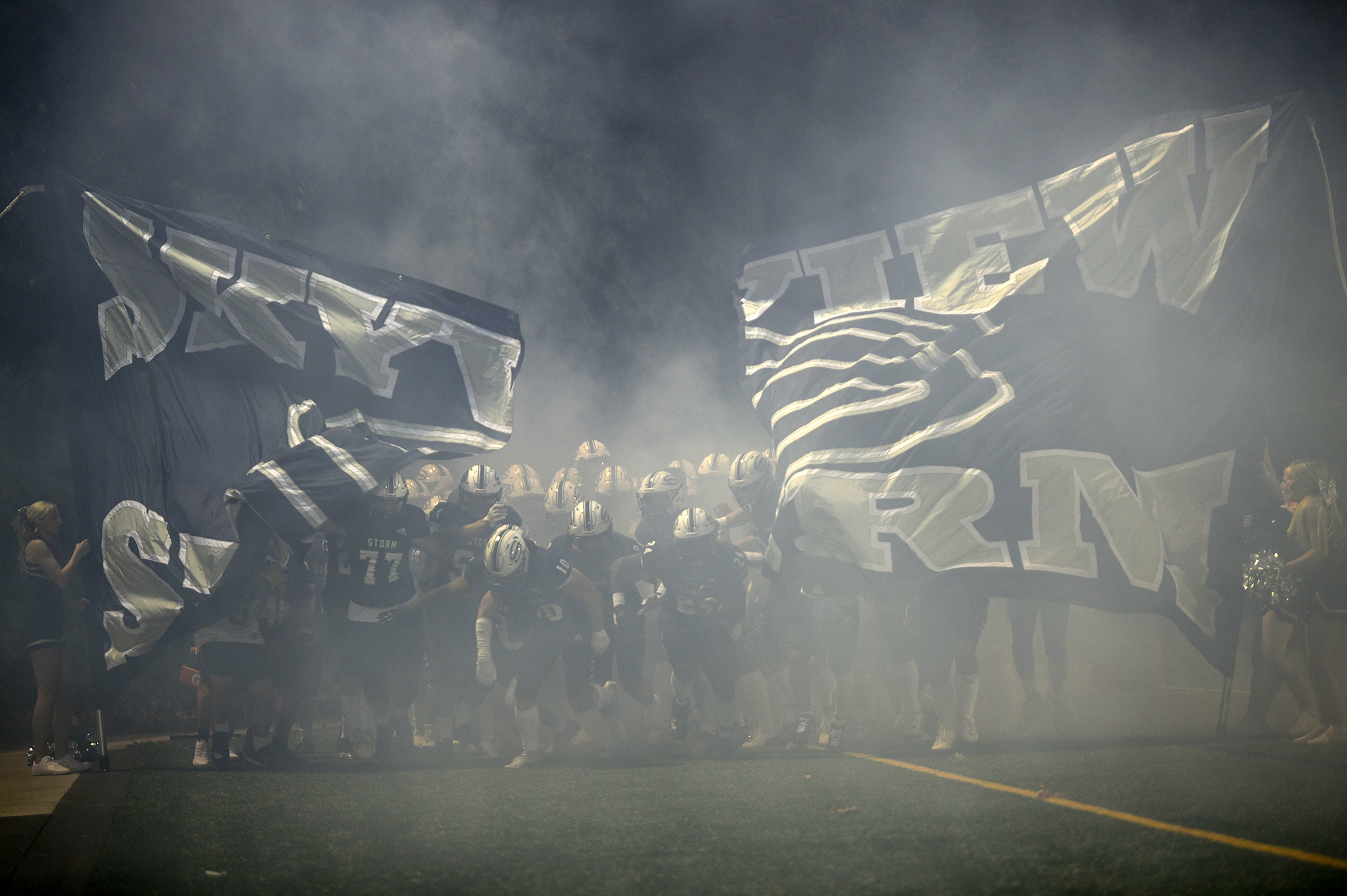 Members of the Skyview football team break through a banner as they take the field at Kiggins Bowl for their game against Jesuit on Sept. 1, 2023.