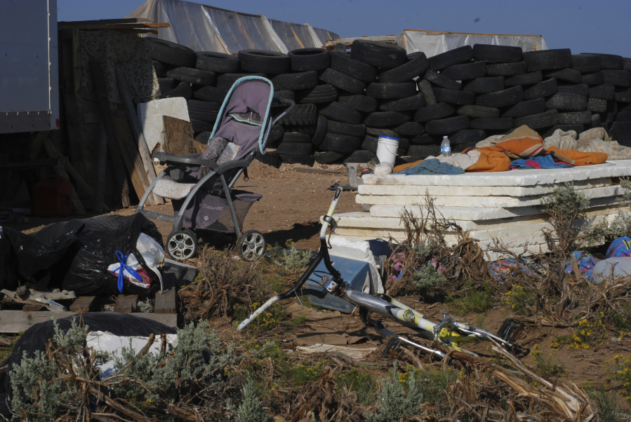 FILE - A children's bicycle and a baby stroller lay inside a squalid makeshift living compound in Amalia, N.M., on Aug. 10, 2018. Two firearms charges were dismissed Thursday, Sept. 21, 2023, amid preparations for trial against an extended family arrested in a 2018 law enforcement raid on the compound in northern New Mexico and the discovery of a young boy's decomposed body.