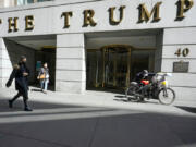 FILE - Pedestrians and a food delivery man are seen outside the Trump building on Wall Street, in New York's Financial District, March 23, 2021. New York Judge Arthur Engoron, ruling in a civil lawsuit brought by New York Attorney General Letitia James, found that Trump and his company deceived banks, insurers and others by massively overvaluing his assets and exaggerating his net worth on paperwork used in making deals and securing loans.