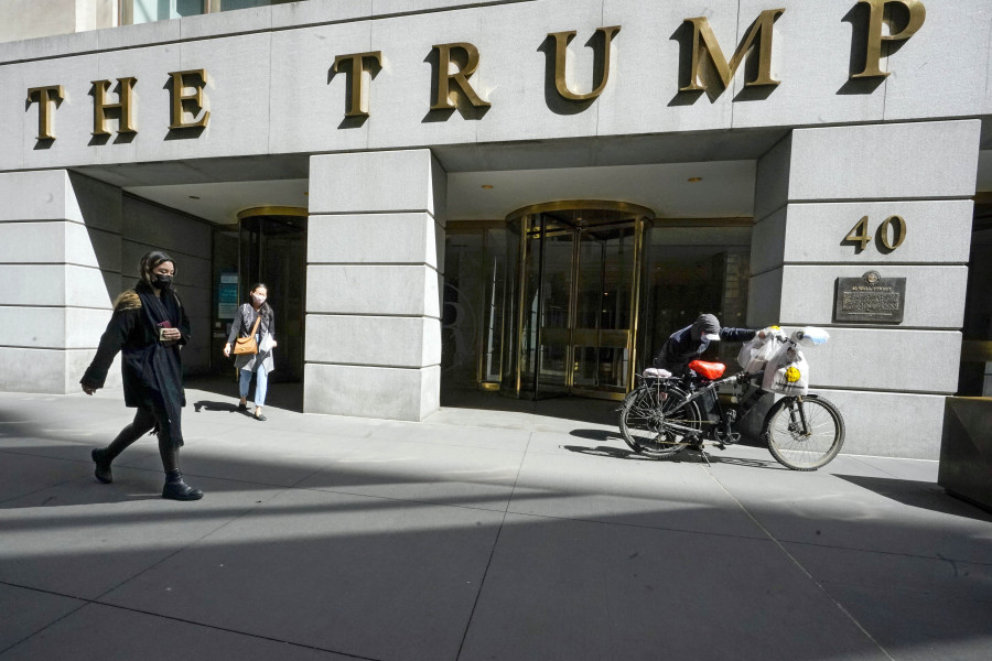 FILE - Pedestrians and a food delivery man are seen outside the Trump building on Wall Street, in New York's Financial District, March 23, 2021. New York Judge Arthur Engoron, ruling in a civil lawsuit brought by New York Attorney General Letitia James, found that Trump and his company deceived banks, insurers and others by massively overvaluing his assets and exaggerating his net worth on paperwork used in making deals and securing loans.