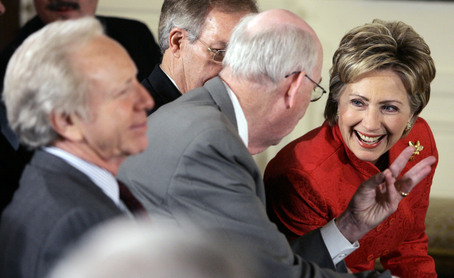 FILE - Democratic presidential hopeful Sen. Hillary Clinton, right, talks with Sen. Robert Bennett, R-Utah, second from left, as Sen. Joseph Lieberman, I-Conn., left, and Sen. Wayne Allard, R-Colo., obscured, looks on prior to President George W. Bush, not shown, spoke during the National Day of Prayer event, May 3, 2007, in the East Room of the White House in Washington.