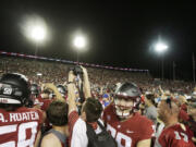 Washington State fans and players celebrate on the field after team's win over Wisconsin in an NCAA college football game, Saturday, Sept. 9, 2023, in Pullman, Wash.