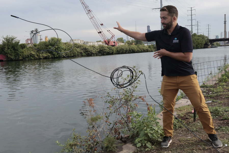 Austin Happel, a research biologist at the Shedd Aquarium, throws a microphone attached to a receiver to track fish in the South Branch of the Chicago River near South Ashland Avenue in Chicago on Sept. 6, 2023.  The Shedd Aquarium looks to understand how habitat restoration initiatives, such as artificial floating wetlands, affect aquatic life. They have launched a new study to track culturally important fish beneath the surface in the South Branch of the Chicago River.