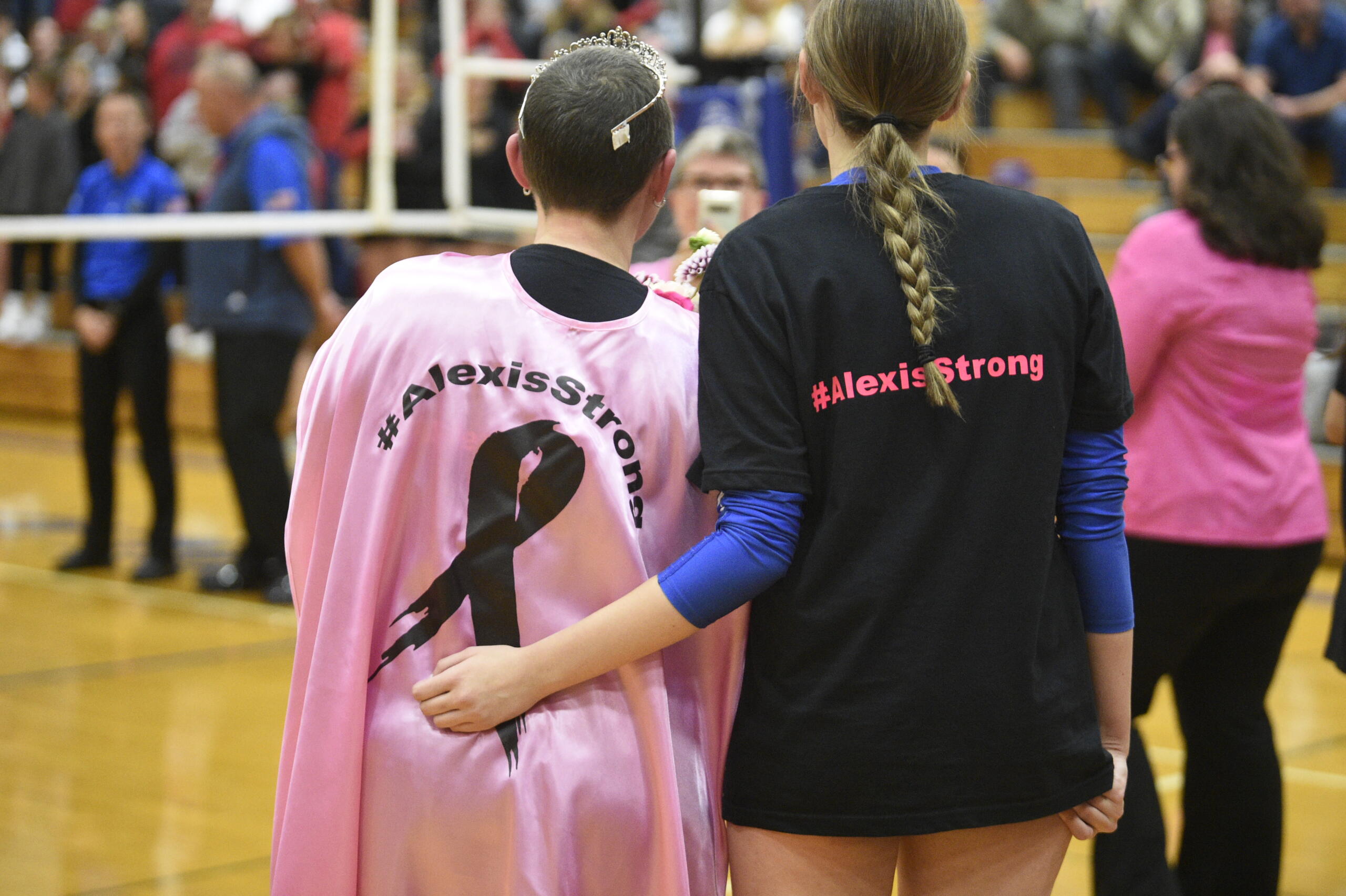 Alexis Mills, left, and her daughter Kylee Mills watch a pre-match ceremony as part of La Center volleyball's Dig Pink night to raise money and awareness of breast cancer on Tuesday, Oct. 10, 2023 at La Center High School. Alexis Mills is battling breast cancer.