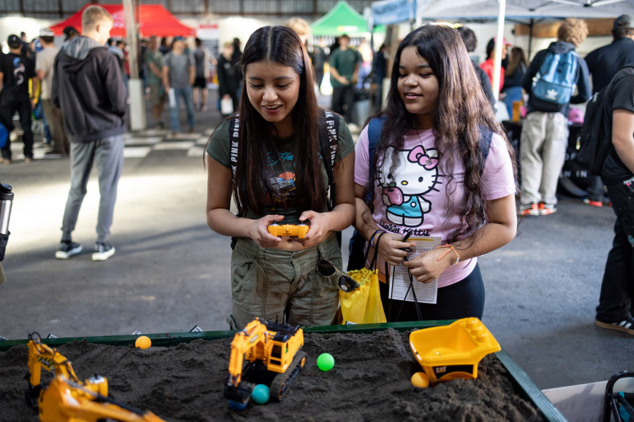 Students Camilla Arelano, left, and Leslie Robles play with toy diggers while exploring career options at the Dozer Day Career Fair.