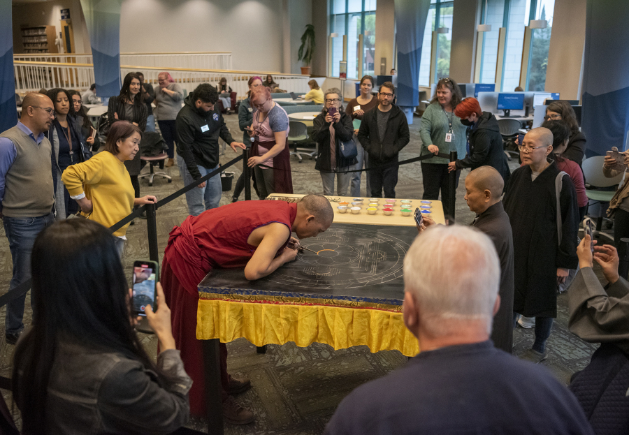 Tibetan Buddhist monk Nawang Shakga, center, works on a sand mandala Monday at Clark College's Cannell Library. A sand mandala is a physical representation of Tibetan Buddhist values of wisdom and compassion; its creation is meticulous and intentional.