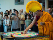Tibetan Buddhist monk Nawang Shakga completes the weeklong sand mandala ceremony by singing, and sweeping the colorful sand into the center of the ceremonial table at Clark College on Friday afternoon.