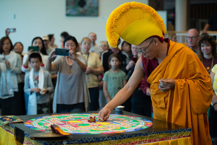 Tibetan Buddhist monk Nawang Shakga completes the weeklong sand mandala ceremony by singing, and sweeping the colorful sand into the center of the ceremonial table at Clark College on Friday afternoon.