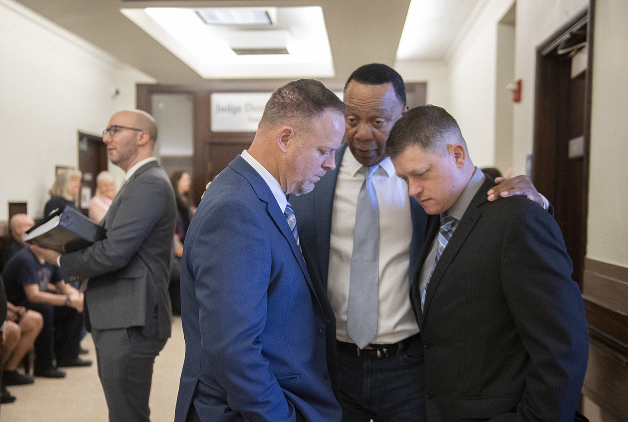 Larch Corrections Center counselor Robert Stricker, blue suit from left, takes a moment to talk with colleagues Sidney Clark and Shawn Piliponis before an injunction hearing concerning the closure of the minimum-security facility, as seen Friday afternoon, Oct. 6, 2023, at the Clark County Courthouse.