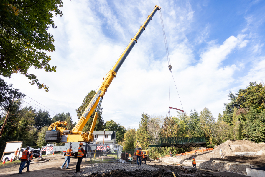 A crane and crews from NessCampbell Crane + Rigging and Tapani Inc. lower a metal bridge into position across a new spillway below a new dam at Columbia Springs, the environmental education campus and trout hatchery in east Vancouver.