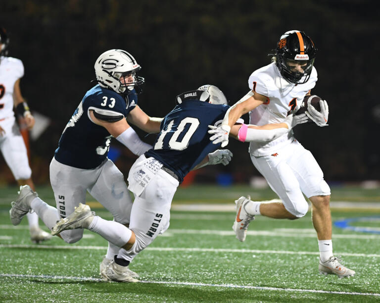 Battle Ground senior Artem Bahnyuk, right, runs with the football and tries to evade tackles from Skyview seniors Kellen Wiggins, left, and Colby Warner on Friday, Oct. 20, 2023, during the Tigers’ 49-10 loss to Skyview at Kiggins Bowl.