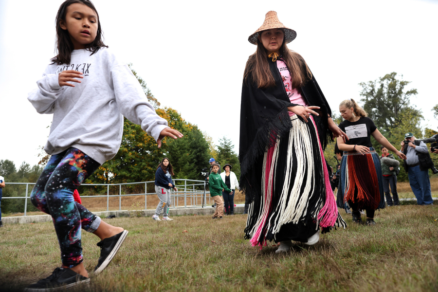 Kaleah Franicis, left, 11, and Malena Marquez, 16, dance to the Salmon Song, a dance that imitates fish swimming up a river, during a ceremony at the fish hatchery marking the Lower Elwha Klallam Tribe???s first fishery on an undammed river in more than 100 years at the Lower Elwha reservation on Monday, Oct. 8, 2023. The subsistence fishery allows the tribe to catch just 400 coho salmon in the Elwha River.