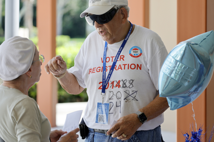Volunteer Joel Davidson speaks with a woman about voting by mail registering to vote by mail outside of the Hagen Ranch Road Library in Delray Beach on National Voter Registration Day, Tuesday Sept. 19, 2023.