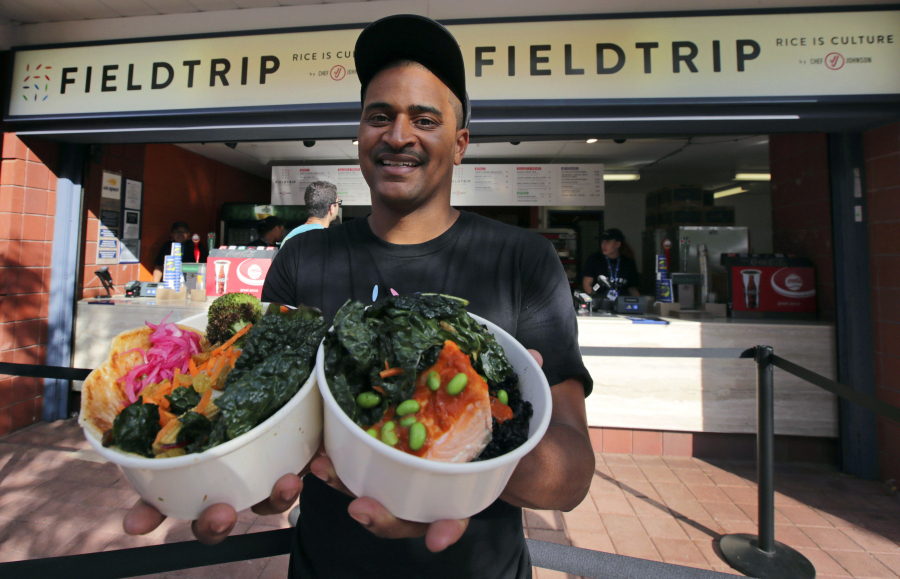 Chef JJ Johnson poses with his two signature rice bowls, one salmon and one vegetable, outside his Field Trip counter-service restaurant kiosk on the food court at the US Open tennis championships in New York.