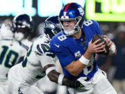 New York Giants quarterback Daniel Jones (8) tries to avoid Seattle Seahawks safety Jamal Adams (33) during the first quarter of an NFL football game, Monday, Oct. 2, 2023, in East Rutherford, N.J.