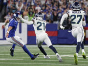 Seattle Seahawks cornerback Devon Witherspoon (21) cuts behind New York Giants quarterback Daniel Jones (8) after intercepting a pass to run it back for a touchdown during the third quarter of an NFL football game, Monday, Oct. 2, 2023, in East Rutherford, N.J.
