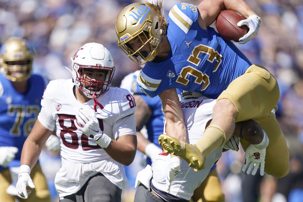 UCLA running back Carson Steele, top, is tackled by Washington State linebacker Devin Richardson, bottom, as defensive tackle Khalil Laufau, left, chases during the first half of an NCAA college football game, Saturday, Oct. 7, 2023, in Pasadena, Calif.
