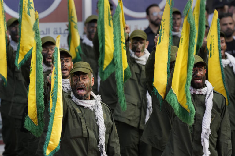 Hezbollah fighters rise their group flags and shout slogans, as they attend the funeral procession of their two comrades who were killed by Israeli shelling, in Kherbet Selem village, south Lebanon, Tuesday, Oct. 10, 2023. The Iran-backed group Monday night announced that three militants died following heavy Israeli shelling in border towns across southern Lebanon.