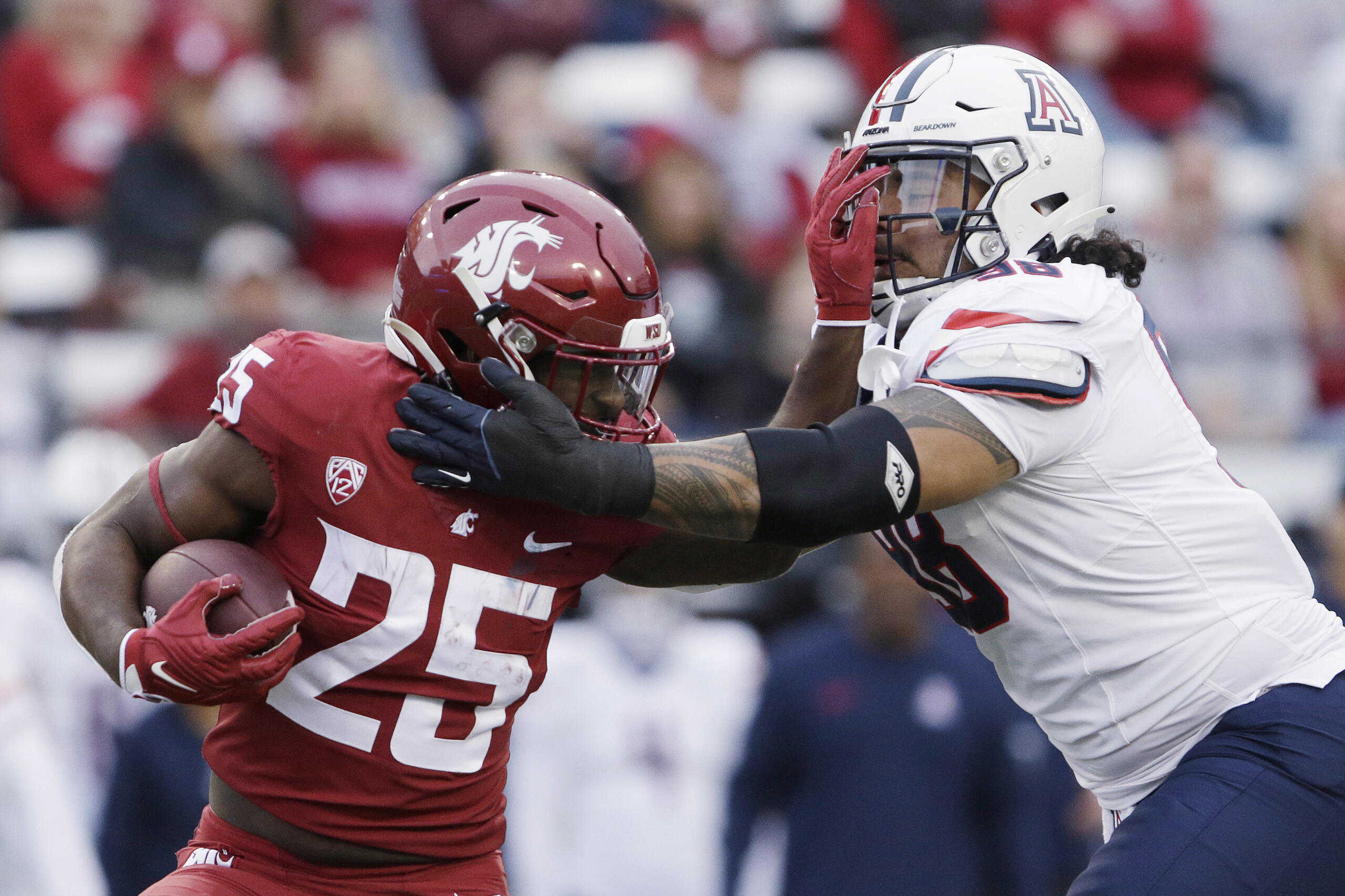 Washington State running back Nakia Watson (25) carries the ball while pressured by Arizona defensive lineman Tiaoalii Savea during the first half of an NCAA college football game Saturday, Oct. 14, 2023, in Pullman, Wash.