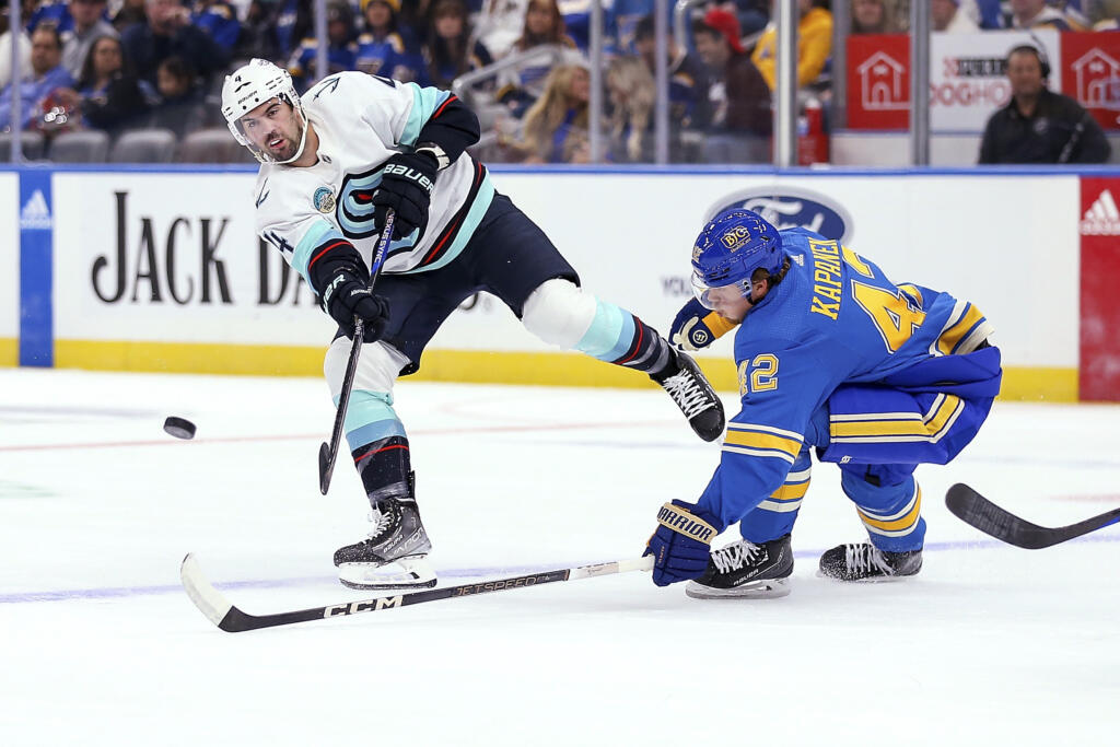 Seattle Kraken's Justin Schultz (4) passes the puck while under pressure from St. Louis Blues' Kasperi Kapanen (42) during the first period of an NHL hockey game Saturday, Oct. 14, 2023, in St. Louis.