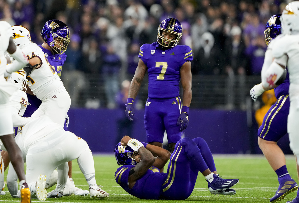 Washington quarterback Michael Penix Jr., bottom, curls up in a ball as running back Dillon Johnson (7) looks on after Arizona State defensive back Shamari Simmons recovered his fumble during the first half of an NCAA college football game Saturday, Oct. 21, 2023, in Seattle.
