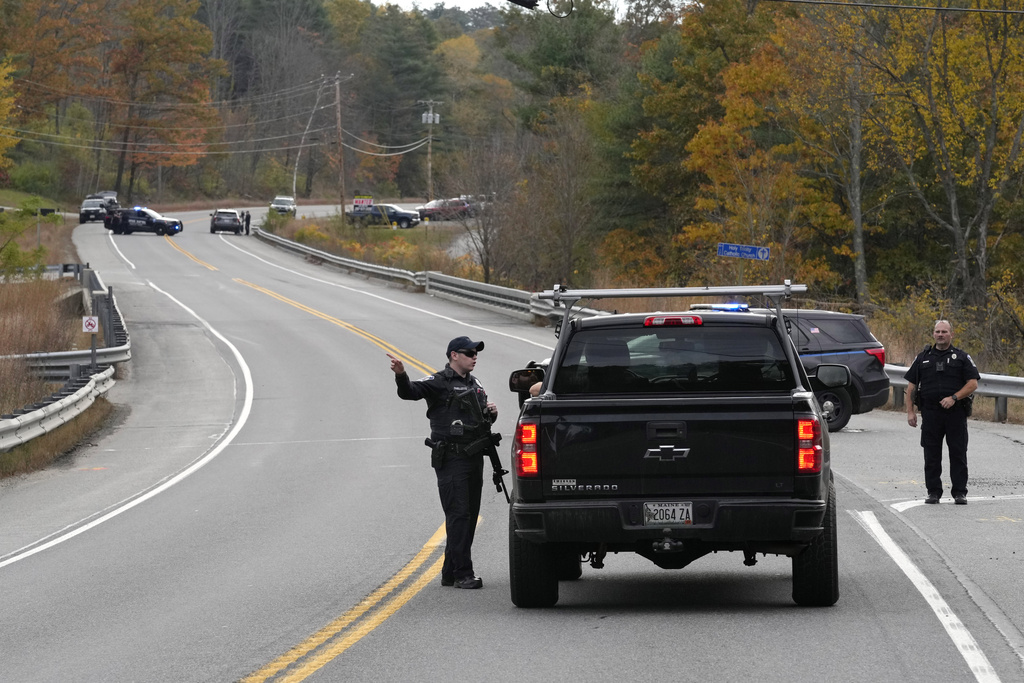 Police officers speak with a motorist at a roadblock, Thursday, Oct. 26, 2023, in Lisbon, Maine, during a manhunt for the suspect of Wednesday's mass shootings. The shootings took place at a restaurant and bowling alley in nearby Lewiston, Maine. (AP Photo/Robert F.