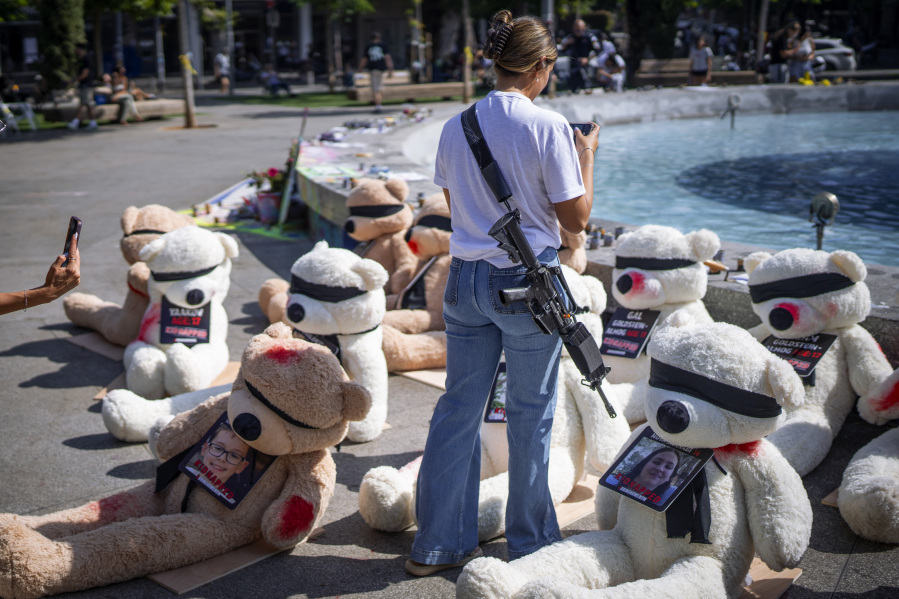 An off-duty Israeli soldier takes photos of an installation of blindfolded giant teddy bears adorned with photos of Israelis held captive in Gaza, in Tel Aviv, Israel, Wednesday, Oct. 25, 2023. The installation is meant to draw attention to over 200 people who were abducted by Hamas militants during a bloody and unprecedented Oct. 7 cross-border attack.