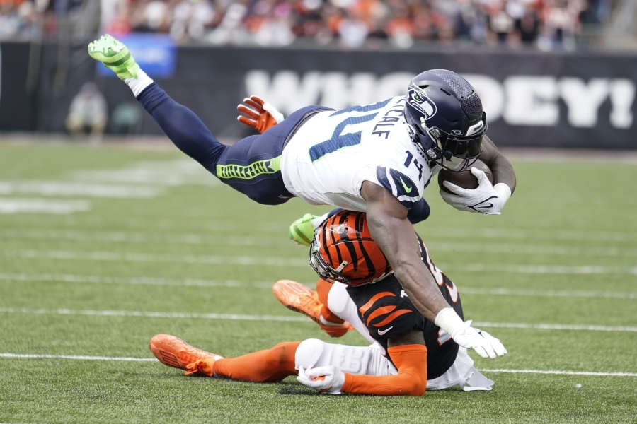 Seattle Seahawks wide receiver DK Metcalf (14) dives over Cincinnati Bengals' Cam Taylor-Britt (29) for a first down during the second half of an NFL football game, Sunday, Oct. 15, 2023, in Cincinnati.