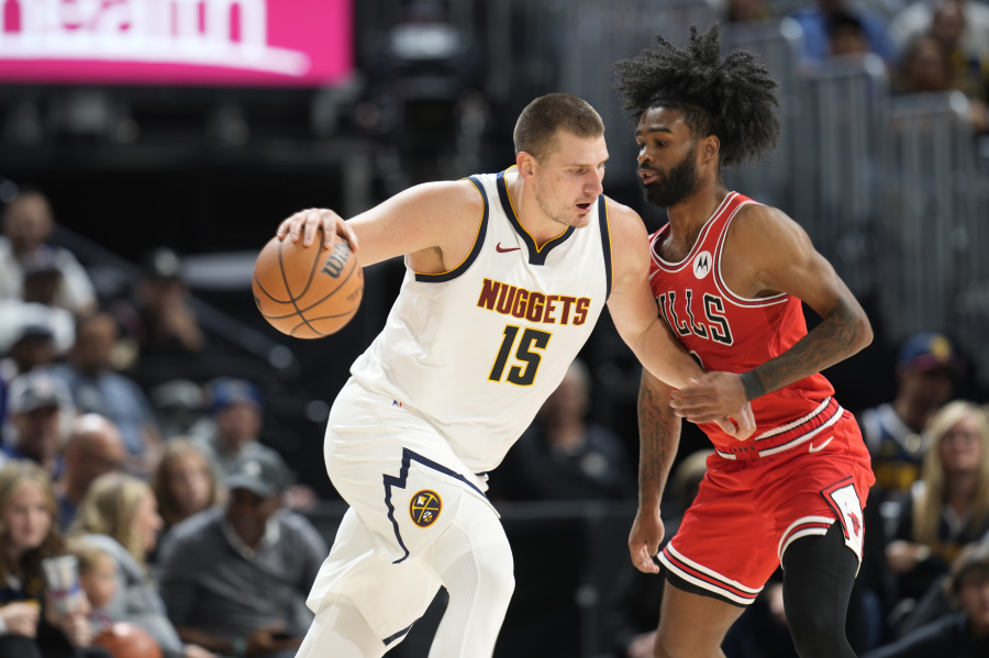 Denver Nuggets center Nikola Jokic, left, drives to the rim as Chicago Bulls guard Coby white defends in the first half of a preseason NBA basketball game Sunday, Oct. 15, 2023, in Denver.