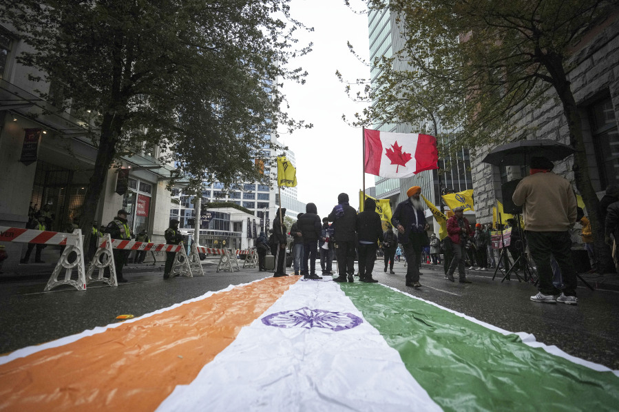 An Indian flag is laid on the street as protesters wave a Canadian and Khalistan flags during a protest outside the Indian Consulate in Vancouver, British Columbia, on Monday, Sept. 25, 2023.