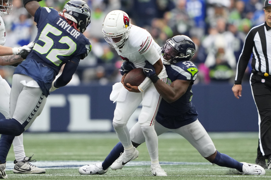 Arizona Cardinals quarterback Joshua Dobbs, center, gets taken down by Seattle Seahawks linebacker Boye Mafe (53) as Seahawks linebacker Darrell Taylor (52) arrives to join in on the tackle during the second half of an NFL football game Sunday, Oct. 22, 2023, in Seattle.