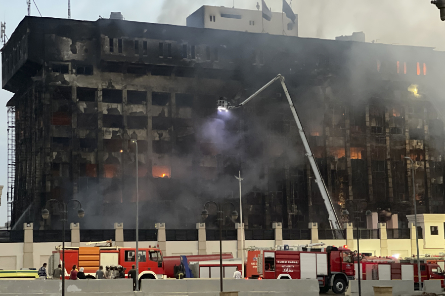 Firefighters climb up a ladder on the burning building of police headquarters in Ismailia, northeastern Egypt following a fire Monday, Oct. 2, 2023. A huge fire broke out early Monday in the police headquarters, injuring multiple people, the health ministry said.