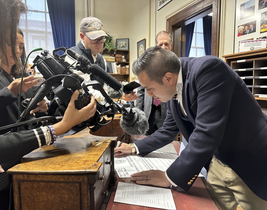 John Anthony Castro, of Texas, signs a commemorative poster after filing to get on the Republican ballot for the 2024 New Hampshire primary in Concord, N.H., on Wednesday, Oct. 11, 2023. Castro, who has filed multiple lawsuits contending the 14th Amendment bars former President Donald Trump's candidacy, wrote: "Freedom comes from our Constitution.