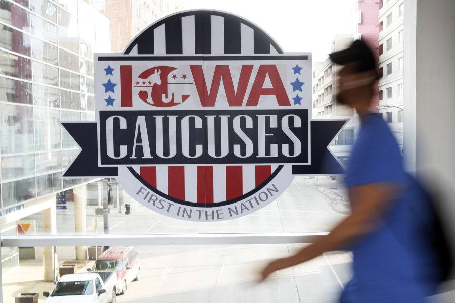FILE - A pedestrian walks past a sign for the Iowa Caucuses on a downtown skywalk, in Des Moines, Iowa, on Feb. 4, 2020. Iowa's Democratic Party says it will hold a caucus on Jan. 15 but won't release the results until early March. It's an attempt to retain their state's leadoff spot on the presidential nominating calendar without violating a new national party lineup endorsed by President Joe Biden that has South Carolina going first for 2024.