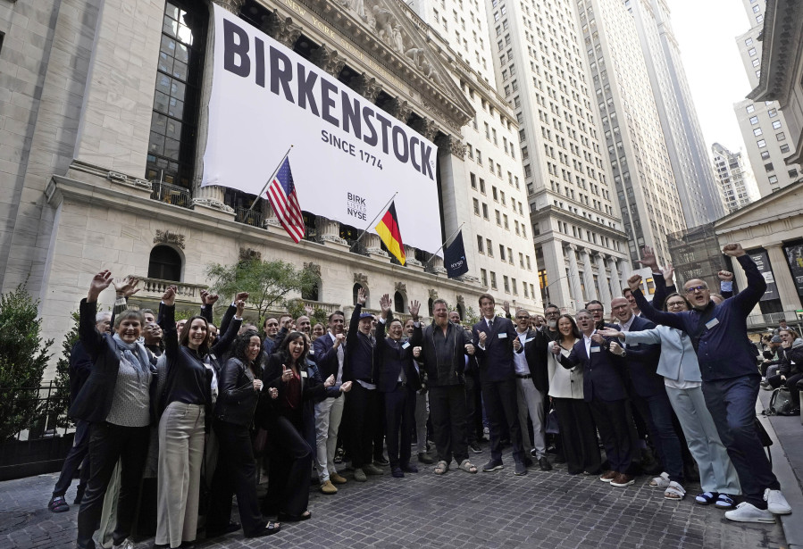 Birkenstock CEO Oliver Reichert, center, and company employees pose for photos outside the New York Stock Exchange, prior to his company's IPO, Wednesday, Oct. 11, 2023.