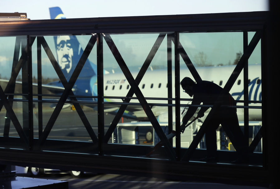 FILE - A worker cleans a jet bridge at Paine Field in Everett, Wash., before passengers board an Alaska Airlines flight on March 4, 2019. Seattle-based Alaska Airlines owns Horizon Air. An off-duty pilot riding in the extra seat in the cockpit of a Horizon Air passenger jet on Sunday, Oct. 22, 2023, tried to shut down the engines in mid-flight and had to be subdued by the crew, according to a pilot flying the plane. (AP Photo/Ted S.