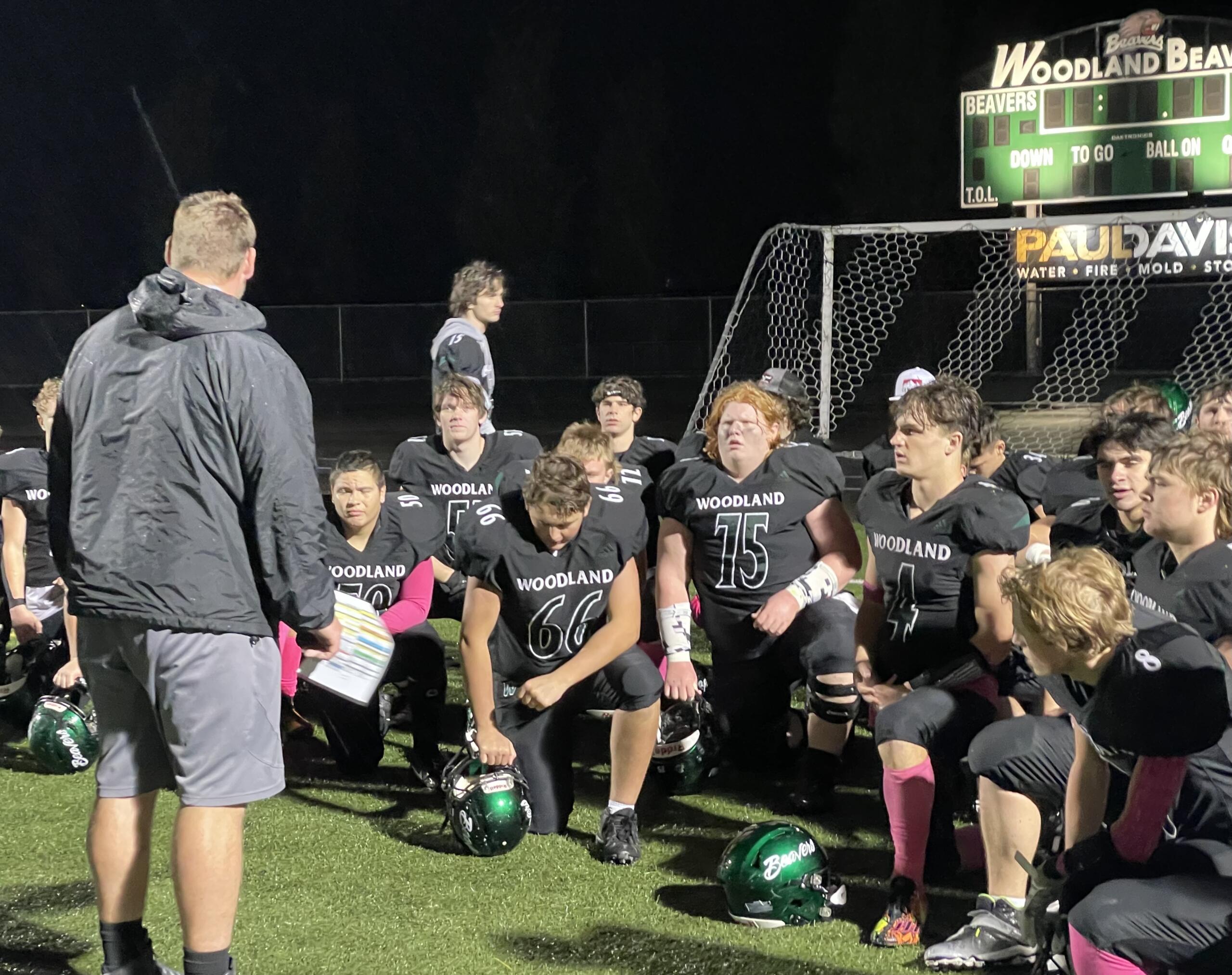 Woodland's Elijah Andersen (4) listens to head coach Sean McDonald during a post-game huddle after the Beavers' 41-10 win over Hudson's Bay on Friday, Oct. 13, 2023, at Woodland High School.