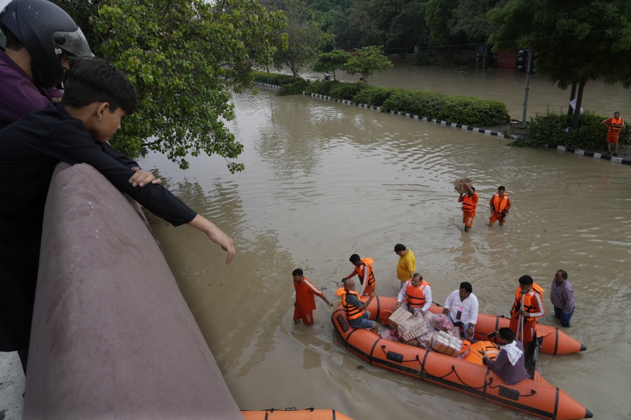 FILE - National Disaster Response Force (NDRF) personnel distribute relief material to flood affected people stuck in a low lying area around the river Yamuna in New Delhi, India, July 14, 2023. The devastation of this year's monsoon season in India, which runs from June to September, has been significant.