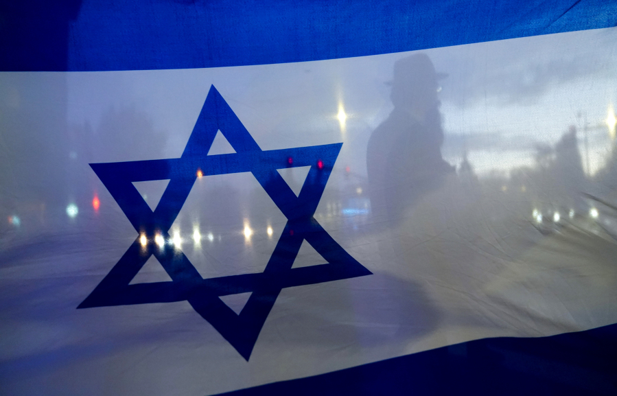 File - A demonstrator is silhouetted behind a flag of Israel during a rally in support of Israel on Oct. 9, 2023, in Bellevue, Wash. Before it transformed into X, Twitter was the place to turn to for live and reliable information about big news events, from wars to natural disasters. But as the Israel-Hamas war has underscored, that is no longer the case.