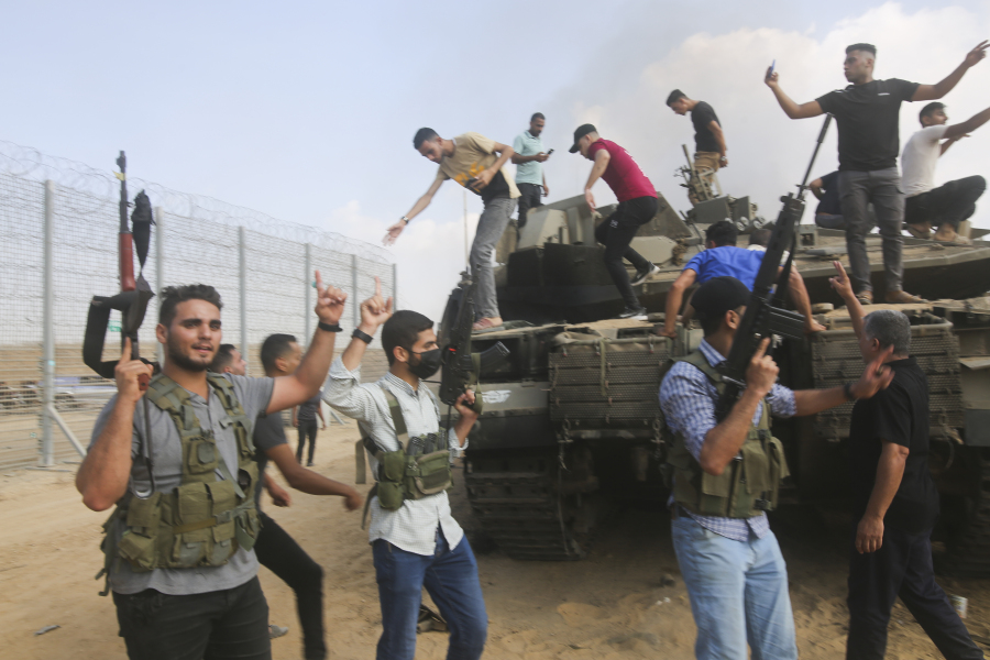 Palestinian militants celebrate by an Israeli tank at the border fence of the Gaza Strip on Saturday, Oct. 7, 2023. The militant Hamas rulers of the Gaza Strip carried out an unprecedented, multi-front attack on Israel at daybreak Saturday, firing thousands of rockets as dozens of Hamas fighters infiltrated the heavily fortified border in several locations by air, land, and sea and catching the country off-guard on a major holiday.