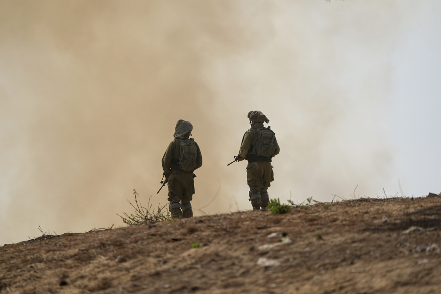 Israeli soldiers stand next to a burning field near the border with the Gaza Strip, in southern Israel, Tuesday, Oct. 24, 2023.