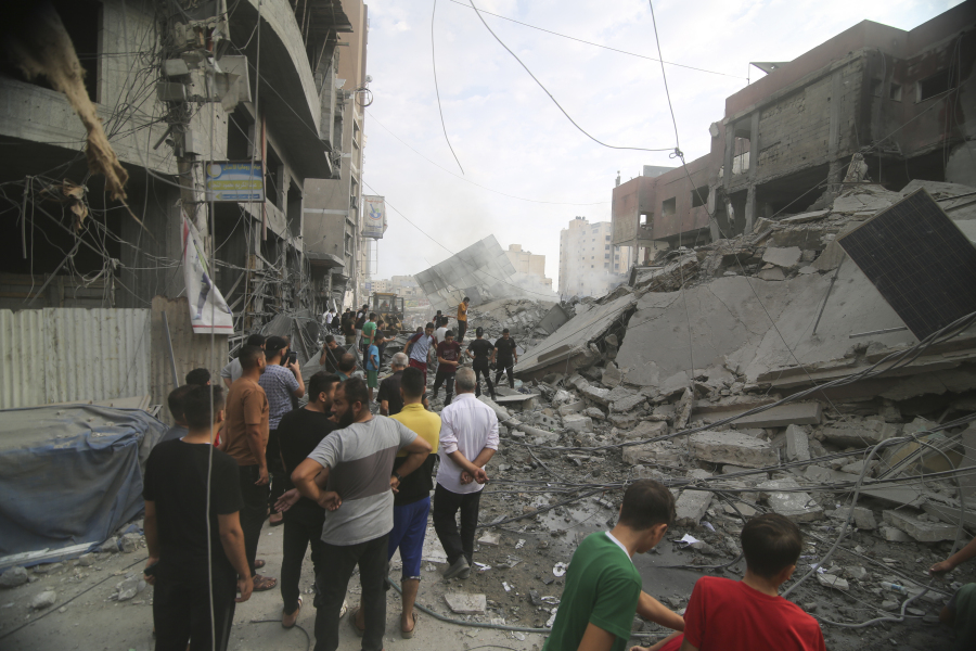 Palestinians inspect the damage of destroyed building after Israeli airstrikes in Khan Younis, Gaza Strip, Tuesday, Oct. 10, 2023.