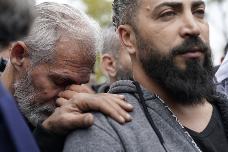 Wadea Al Fayoume's father, Oday Al Fayoume, right, and his uncle Mahmoud Yousef mourn at Wadea's grave in LaGrange, Ill., Monday, Oct. 16, 2023. An Illinois landlord accused of fatally stabbing the 6-year-old Muslim boy and seriously wounding his mother was charged with a hate crime after police and relatives said he singled out the victims because of their faith and as a response to the war between Israel and Hamas. (AP Photo/Nam Y.